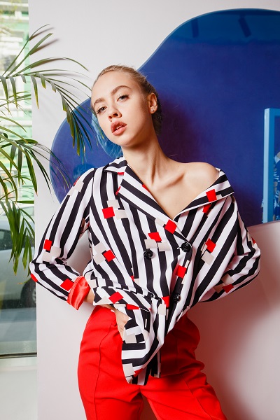 Fashionable young Ukrainian girl blogger dressed in a stylish striped shirt and red trousers